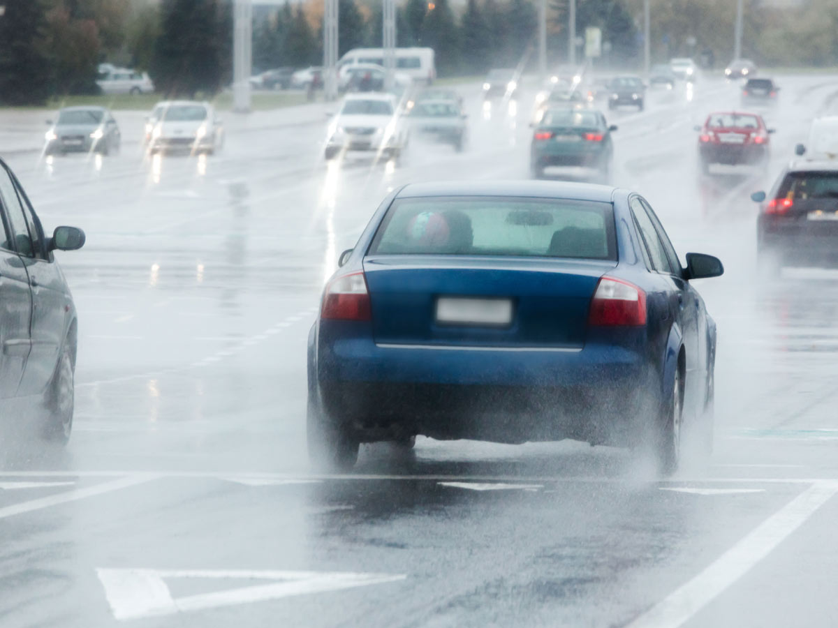 Blue car driving on a rainy road in traffic
